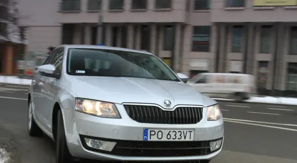Srebrna Skoda Octavia 1.6 TDI jedzie ulicą miasta.