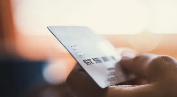 Dłoń trzyma kartę płatniczą. Zastanawiasz się, moneyback co to? To zwrot części pieniędzy za zakupy.