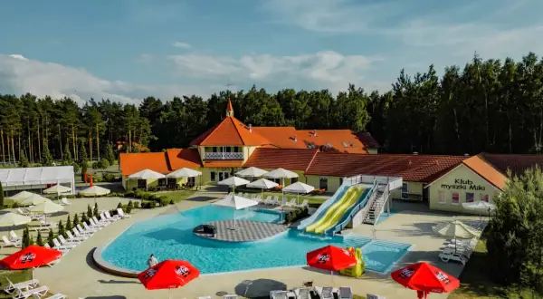Basen z atrakcjami i zjeżdżalniami, idealny na hotelowe animacje dla dzieci. Słoneczny dzień, dużo leżaków i parasoli.