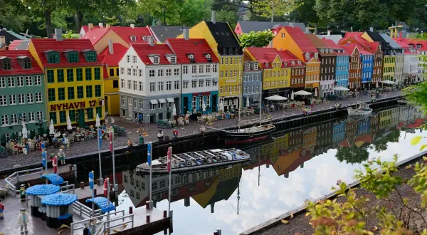 Kolorowe kamienice Nyhavn w Legoland Dania atrakcje, odbijające się w wodzie. Miniaturowe łodzie i ludzie dodają uroku.