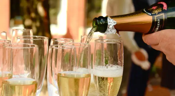 Nalewanie złotego **brut wino** do kieliszków. Bąbelki unoszą się, zapowiadając celebrację.