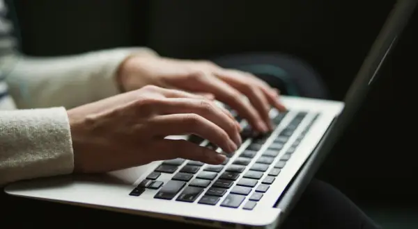 Dłonie piszą na laptopie, szukając informacji o antimalware service executable co to jest i jak działa.