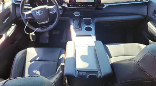 Wnętrze Toyoty Sienna Hybrid: czarne skórzane fotele, kierownica, deska rozdzielcza z ekranem nawigacji.