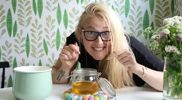 Glad kvinna visar upp sin hemgjorda ghee. Enkel guide för hur man gör ghee.