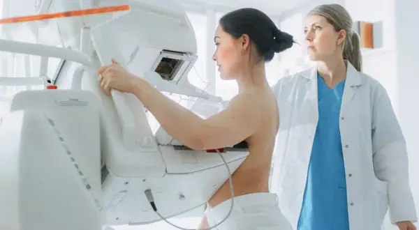 Kobieta podczas mammografii, gdzie zacienienie w mammografii co oznacza jest kluczowe dla diagnozy. Lekarka nadzoruje badanie.