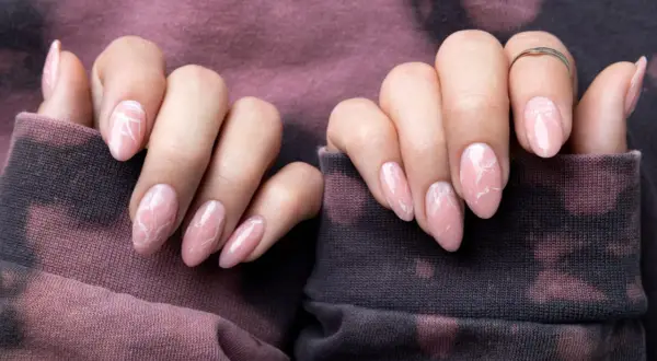 Delikatne, różowe paznokcie z białym wzorem marmuru. Inspiracja z "1001 pomysłów na paznokcie" na subtelny manicure.