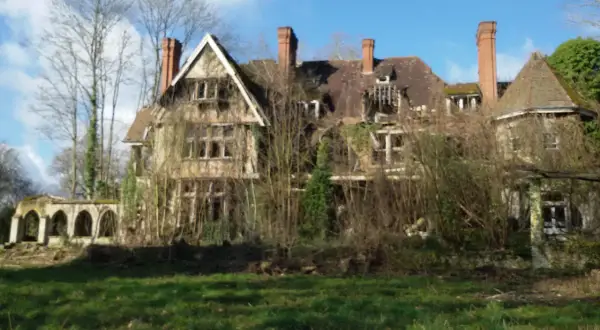 Maison abandonnée envahie par la végétation, un vestige de l'urbex Sarthe. Le toit est délabré, les fenêtres brisées, et la nature reprend ses droits.