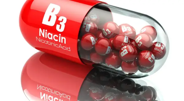 Czerwona kapsułka wypełniona małymi kulkami z napisem "Niacin B3". To niacynobaza w pigułce.