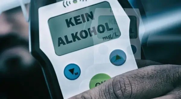 Dłoń trzyma alkomat z napisem "KEIN ALKOHOL" na wyświetlaczu.