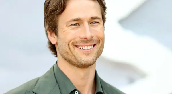 Lachender Glen Powell in grünem Anzug, bereit für neue Filme.