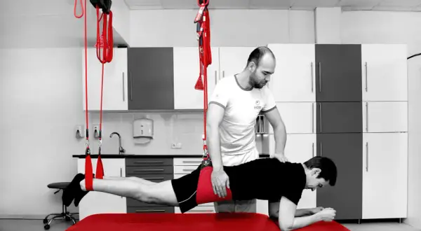 Fizjoterapeuta pomaga pacjentowi w ćwiczeniach rehabilitacyjnych, które mogą być częścią leczenia koślawości bioder.