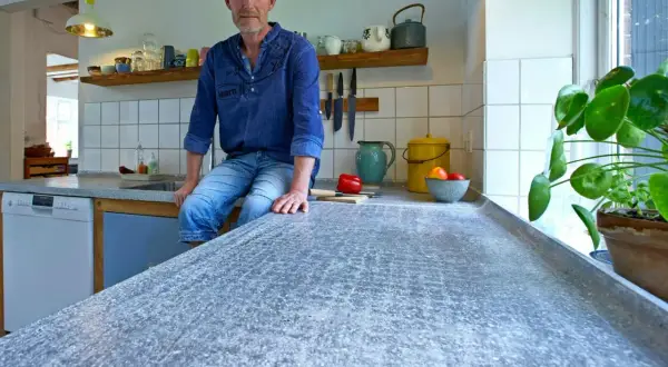 Man sitter på en köksbänk med en betongskiva som är behandlad för att få en unik textur.