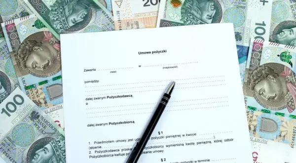Umowa pożyczki na tle polskich banknotów. Szukasz informacji, gdzie pożyczki dla zadłużonych są dostępne? Dokument i pieniądze sugerują rozwiązanie.