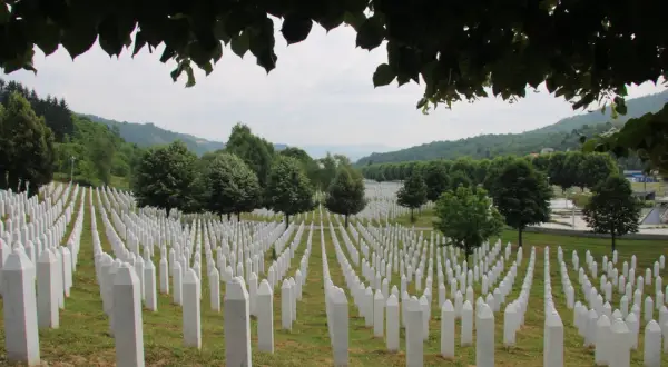 Enormt fält med vita gravstenar, en påminnelse om folkmordet i Srebrenica. Grönskande kullar i bakgrunden.