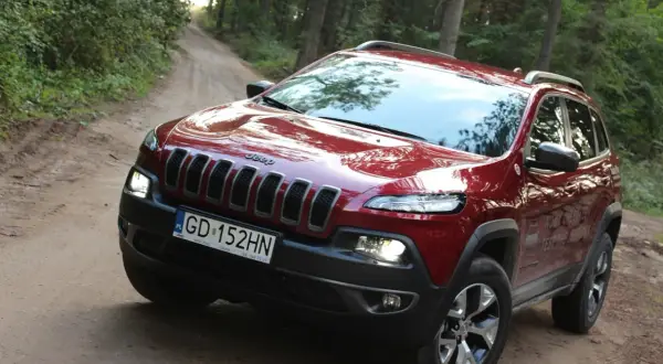 Czerwony Jeep Cherokee Trailhawk na leśnej, piaszczystej drodze. Gotowy na przygodę.
