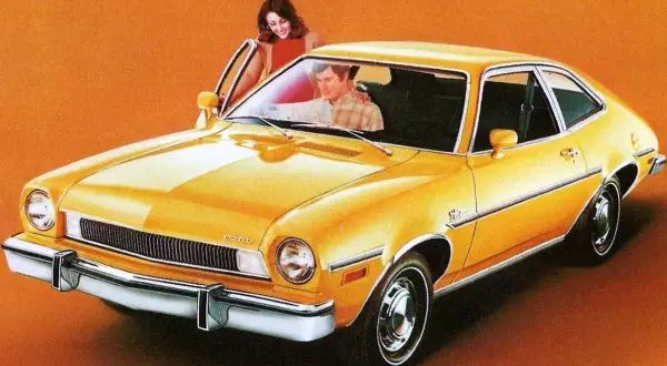 Gul Ford Pinto med en kvinna som öppnar dörren och en man i förarsätet.