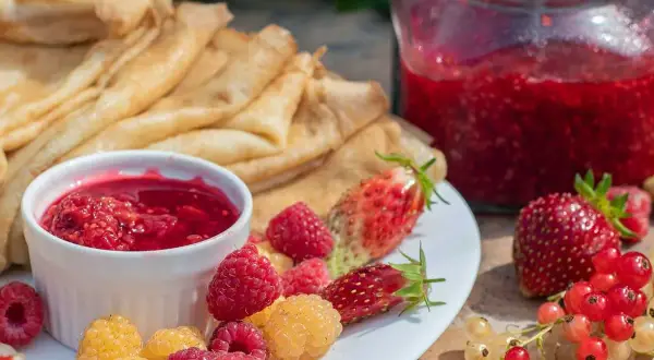Färska hallon, jordgubbar och vinbär till ett härligt hallonsylt recept. Pannkakor och sylt i en härlig sommardukning.