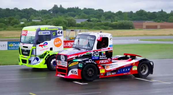 Deux camions de course s'affrontent sur le circuit. Le camion vert vif et le camion rouge et noir sont prêts pour le grand prix camion Nogaro.