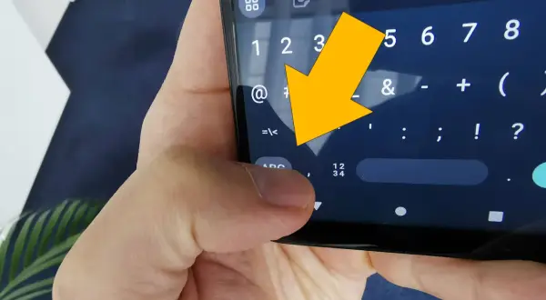 Żółta strzałka wskazuje na klawiaturę telefonu, na znak "<".