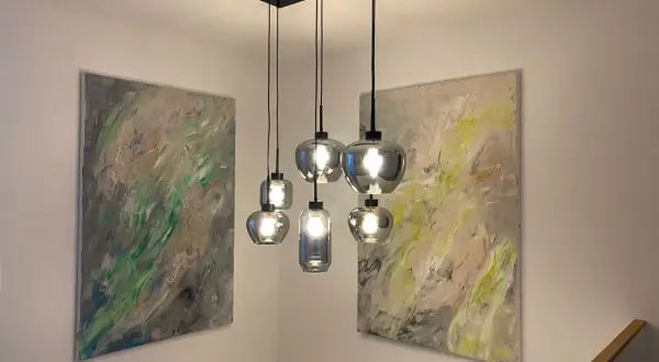 Moderne Hängelampen montieren über einem Treppenaufgang, flankiert von abstrakter Kunst.