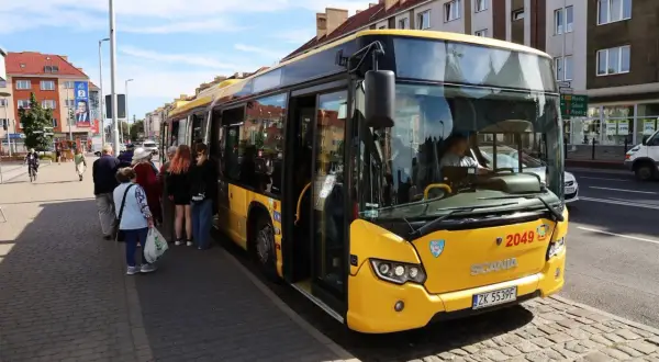 Żółty autobus PKS czeka na pasażerów w Koszalinie, gotowy do podróży do Dąbek.