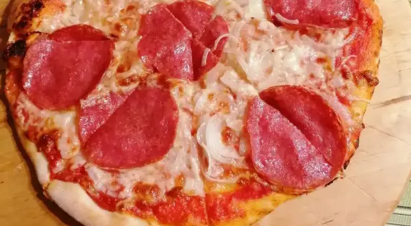 Pizza z pepperoni i cebulą, zrumieniona skórka, roztopiony ser.