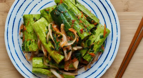 En tallrik med krispig gurka marinerad i en kryddig kimchi-sås, redo att avnjutas som ett läckert recept med kimchi.