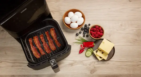 Krispigt bacon i airfryer, redo för en god frukost med ägg, bär och ost.