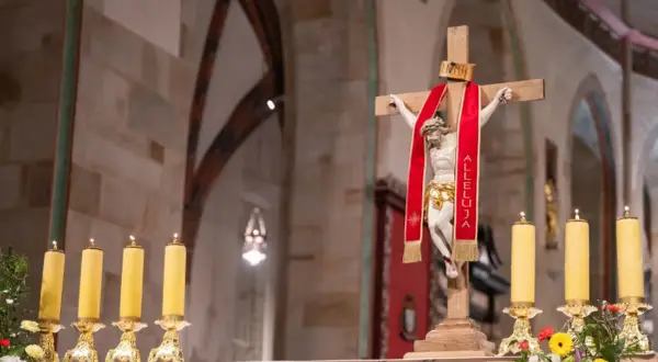 Chrystus na krzyżu z czerwoną wstęgą "Alleluja". Obok płonące świece. 25 marca święto kościelne.