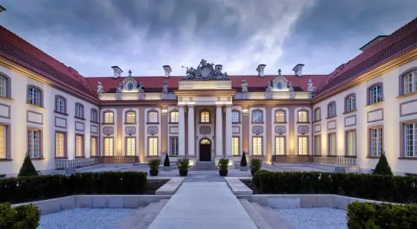 Elegancki pałac z czerwonym dachem i oświetlonymi oknami, wieczorem.