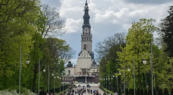 Aleja prowadząca do imponującego sanktuarium w Polsce. Tłumy pielgrzymów zmierzają ku wieży klasztoru.
