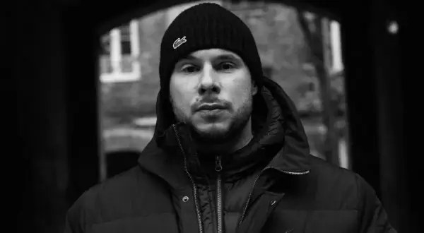 Portret młodego mężczyzny w czapce z logo Lacoste, jednego z wielu polskich raperów, który tworzy muzykę uliczną.