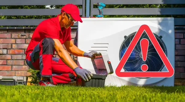 Un technicien en rouge ouvre sa boîte à outils près d'une pompe à chaleur. Un panneau d'avertissement rouge indique que ma pompe à chaleur se met en sécurité.