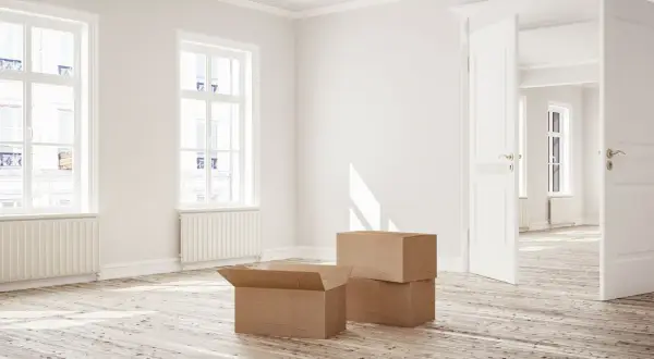 Appartement vide avec cartons, prêt à emménager. La lumière du soleil traverse les fenêtres, évoquant un nouveau départ, peut-être grâce à la loi Borloo.