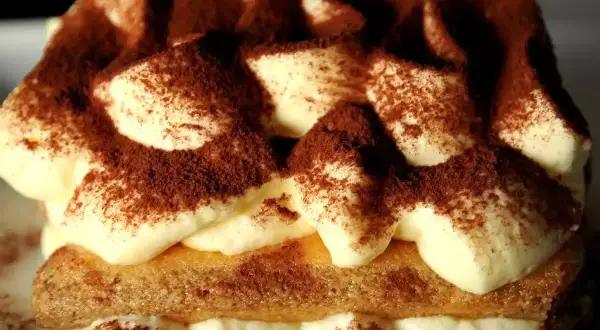 Un délicieux tiramisu au marsala, garni de cacao, avec des couches de crème onctueuse et de biscuits savoyards.