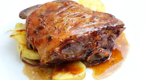 Ternasco asado jugoso y dorado, servido sobre patatas. ¡La mejor opción donde comer ternasco en Zaragoza!