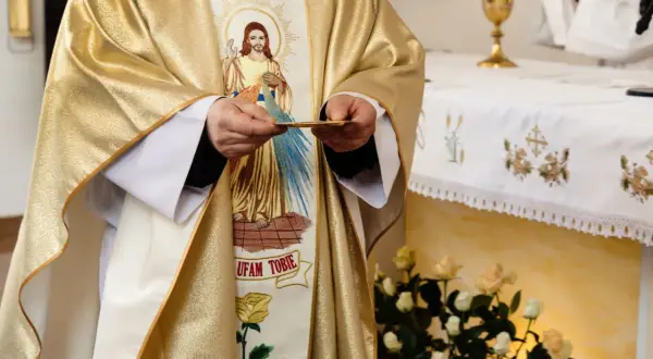 19 czerwca. Kapłan w złotej szacie z wizerunkiem Jezusa trzyma hostię.