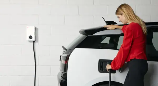 Femme branchant sa voiture électrique sur une borne. Une solution pratique pour le crédit d'impôt borne électrique.