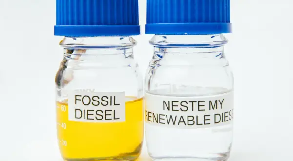 Två provrör med blå korkar. Ett innehåller gulaktig fossil diesel, det andra klar Neste my renewable diesel.