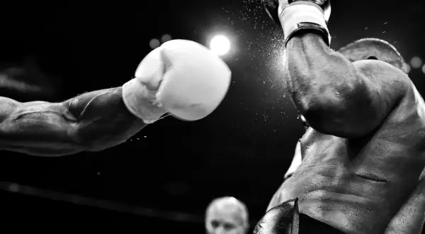 Un pugno in arrivo, un momento catturato da fotografi sportivi famosi. La polvere vola, l'intensità è palpabile.