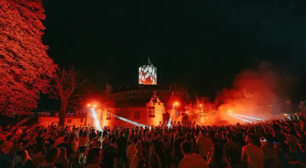 Nocny festiwal w twierdzy z tłumem ludzi i pokazem świateł.