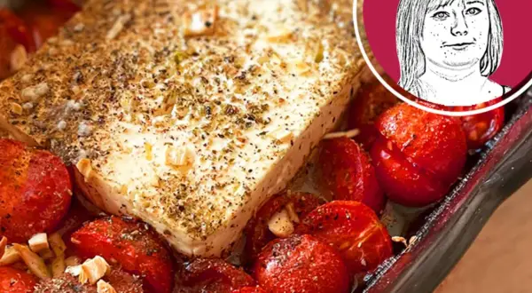 Ein Block Feta mit Kräutern und Gewürzen, umgeben von gebackenen Kirschtomaten. Perfekt für ein schnelles Gericht mit Nudeln mit Feta.