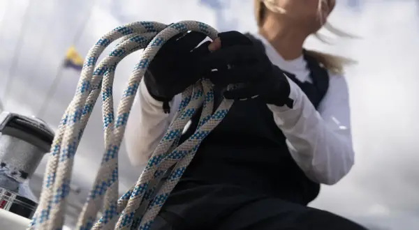 Seglerin mit Handschuhen hält Tauwerk, das für die wichtigsten Knoten auf einem Boot unerlässlich ist.