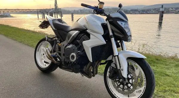 Biały motocykl turystyczny Honda zaparkowany nad rzeką o zachodzie słońca.