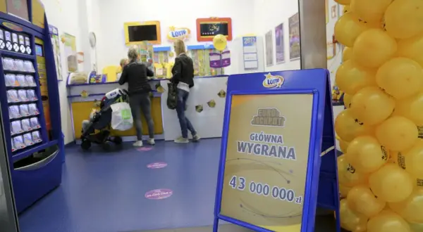 Tablica informacyjna Eurojackpot z kwotą wygranej i żółte balony w punkcie Lotto.