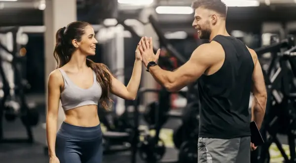 Coppia si dà il cinque in palestra, ispirata da schede palestra con immagini per un allenamento efficace.