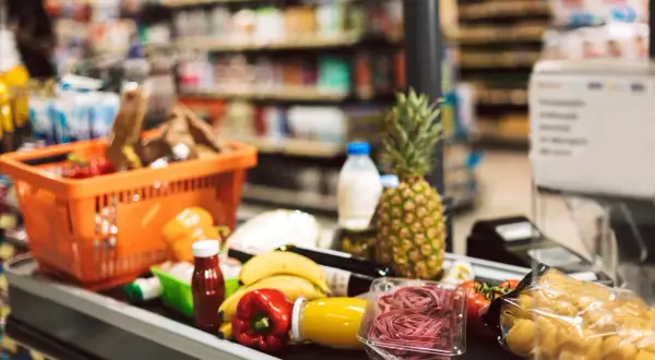 Koszyk z zakupami na taśmie w supermarkecie. Owoce, warzywa, makaron i napoje – typowe produkty FMCG, czyli szybko zbywalne towary.