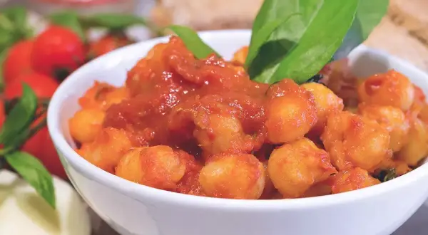 Gnocchi al pomodoro in una ciotola bianca, guarniti con basilico fresco. Un'idea su come condire gli gnocchi per un piatto saporito.