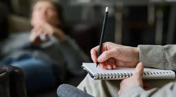 Psycholog słucha i notuje, pomagając pacjentowi zrozumieć siebie.