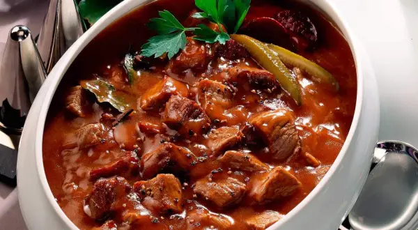 Herzhaftes Pfefferpotthast Rezept in einer Schüssel, garniert mit Petersilie und Gewürzgurken. Ein Klassiker der westfälischen Küche.
